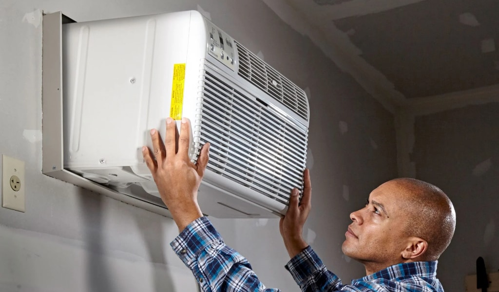 man installing an air conditoner in an alcove